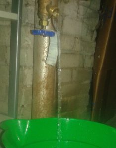 water draining from a spigot into a green bucket